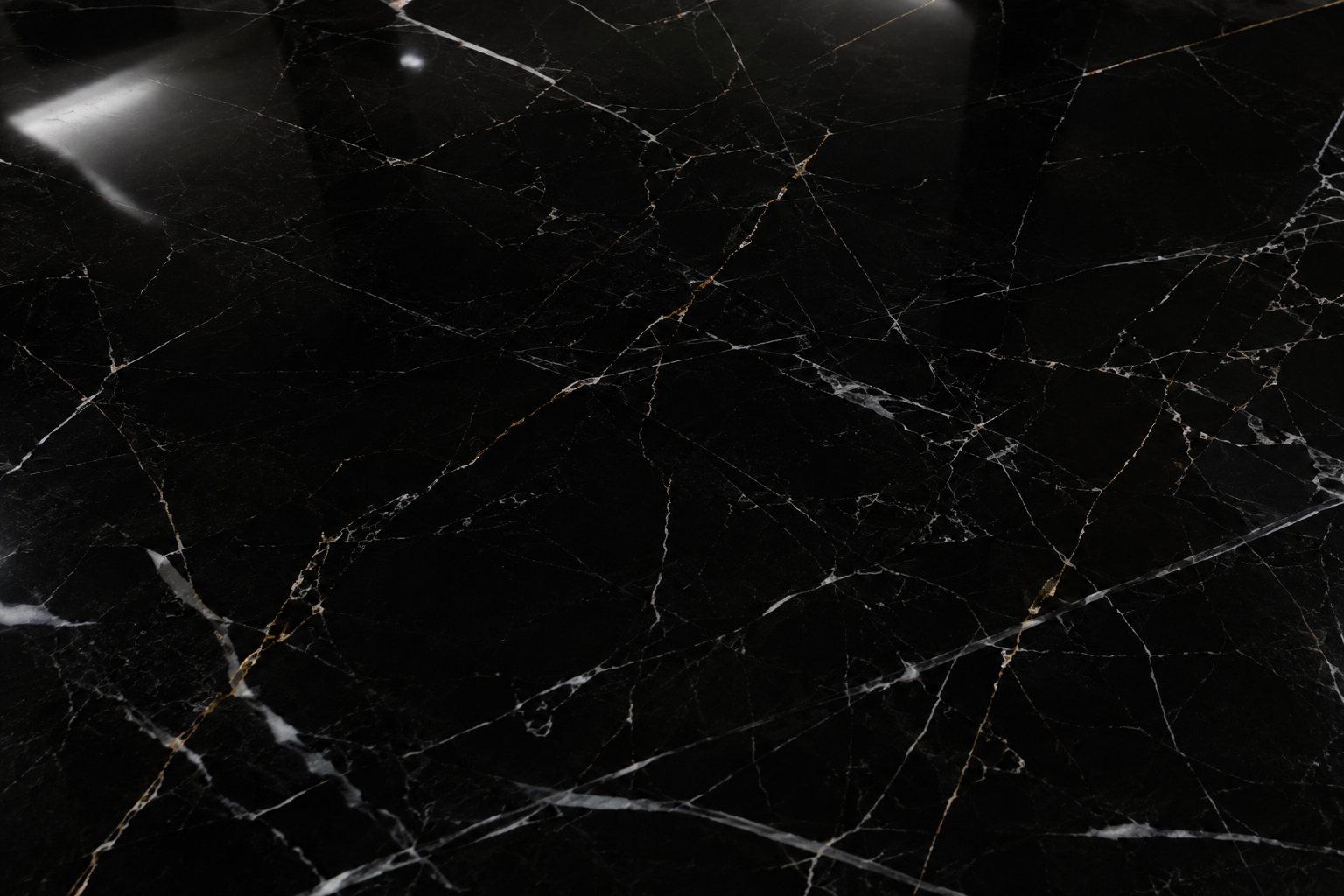 Marquina preto com acabamento polido: superfície espelhada, refletindo o ambiente, com o veio branco em alto contraste.
