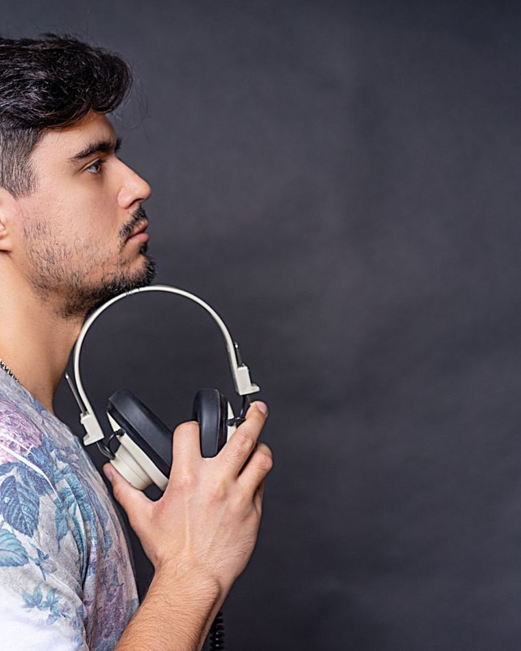 Retrato de NOKTVRNO, DJ, com fones de ouvido sobre fundo escuro.