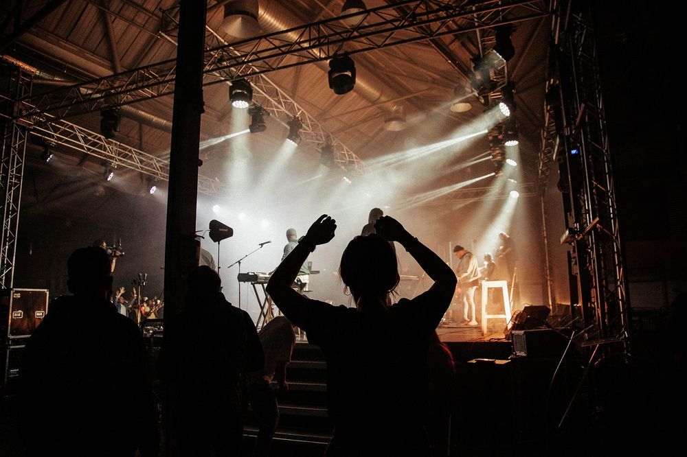 Palco visto de trás do público, com refletores brancos abertos.
